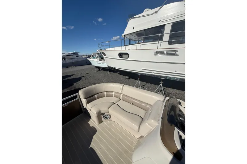 Slide: The Image of 2016 Bennington SX22 boat interior with beige seating, docked near other boats. - 12