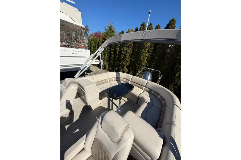 Slide: The Image of 2016 Bennington SX22 pontoon boat with beige seating and a black table under a blue sky. - 15