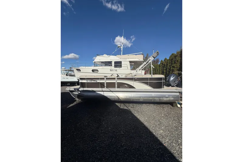 Slide: The Image of 2016 Bennington SX22 pontoon boat on gravel lot under clear blue sky. - 2