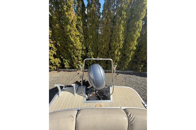 Slide: The Image of 2016 Bennington SX22 pontoon boat with motor, surrounded by lush greenery. - 6