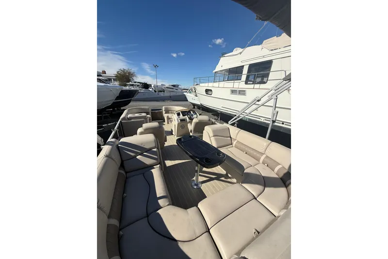 Slide: The Image of 2016 Bennington SX22 pontoon boat with spacious seating and table, docked under clear skies. - 9