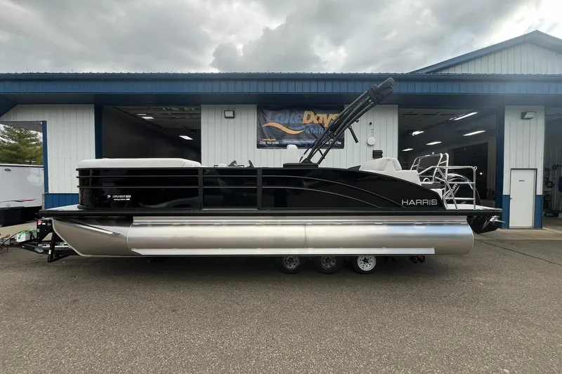 The Image of 2026 Harris Cruiser 230 pontoon boat parked outside a marina building. - 1