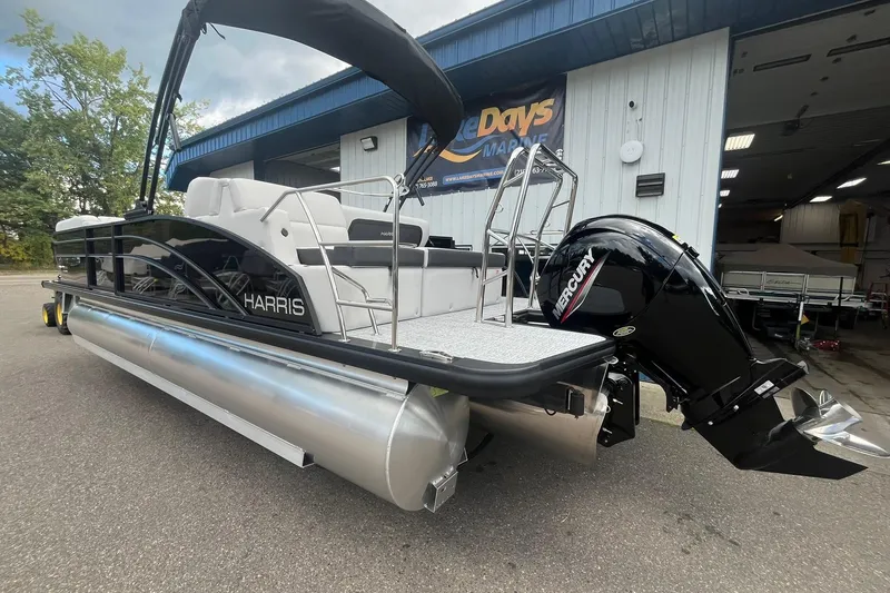Slide: The Image of 2026 Harris Cruiser 230 pontoon boat with Mercury engine, parked outside a marine shop. - 26