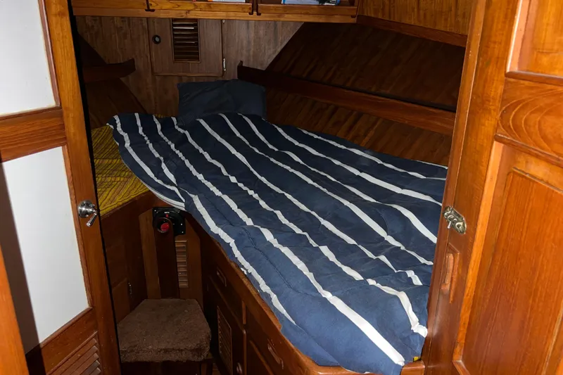 Slide: The Image of 1979 Litton Trawler interior with wooden helm, cozy cabin, and striped bedding. - 12