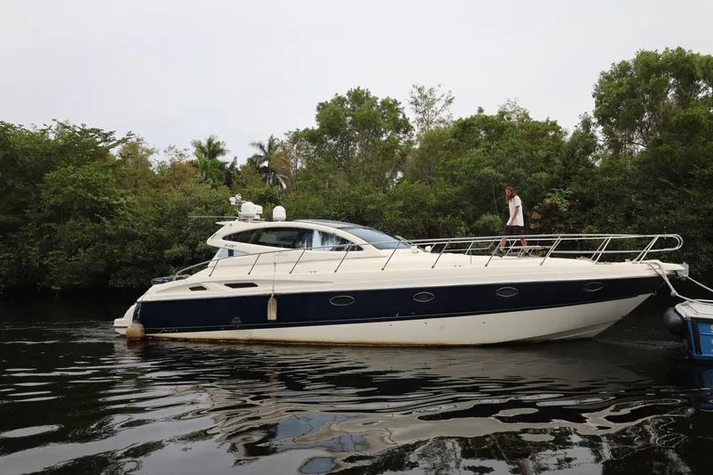 The Image of 2007 Cranchi Mediterranee 50 HT yacht on a calm river, surrounded by lush greenery. - 0