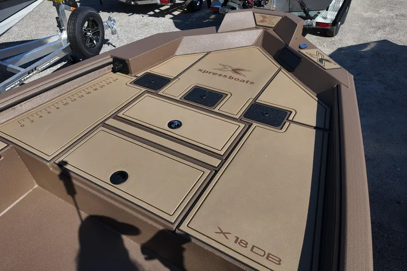 Slide: The Image of 2026 Xpress X18DB boat deck with storage compartments and measuring ruler. - 9