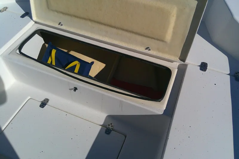 Slide: The Image of Open storage compartment on 2017 Outcast 19V boat with visible blue and yellow bag. - 19