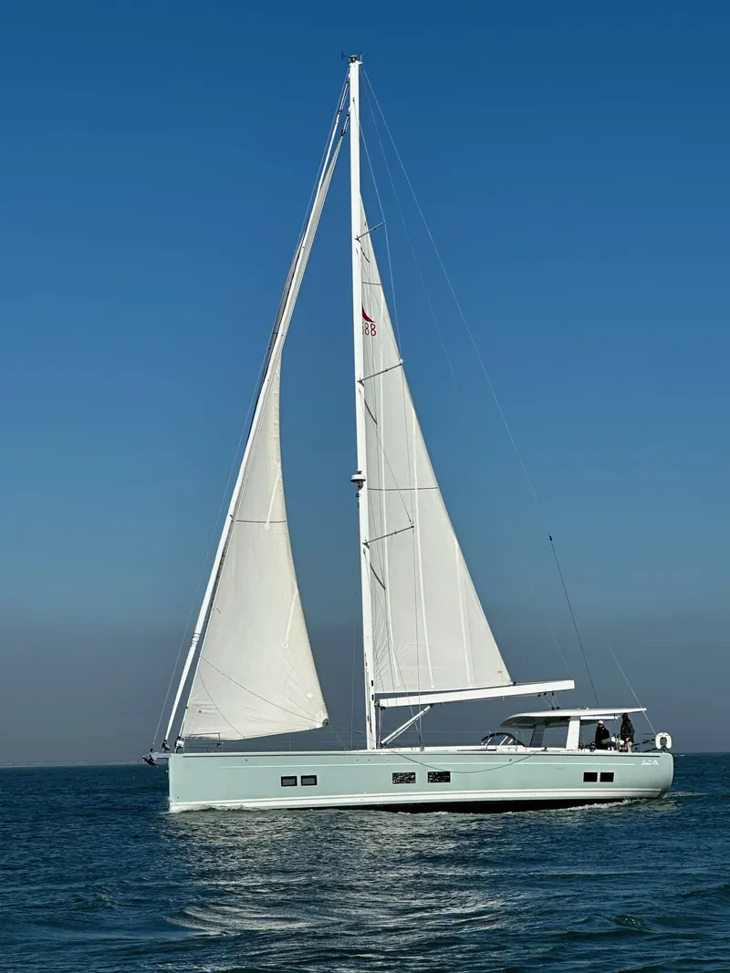 Slide: The Image of 2019 Hanse 588 yacht sailing on open water under clear blue sky. - 1