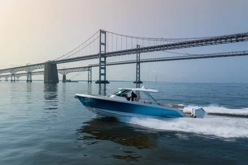 The Image of 2024 Tiara Yachts 43 LS cruising under a large suspension bridge on calm waters. - 0