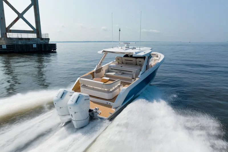 Slide: The Image of 2024 Tiara Yachts 43 LS cruising on open water near a bridge. - 2