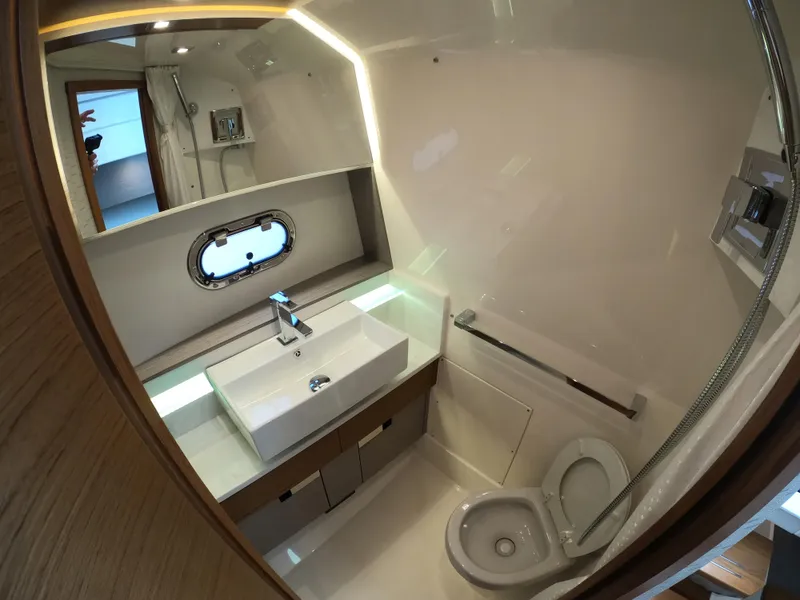 Slide: The Image of 2024 Tiara Yachts 43 LS bathroom with modern sink, toilet, and porthole window. - 27
