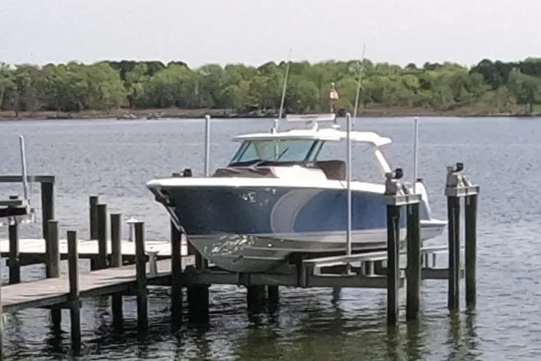Slide: The Image of 2024 Tiara Yachts 43 LS docked on a serene lake with lush green background. - 5