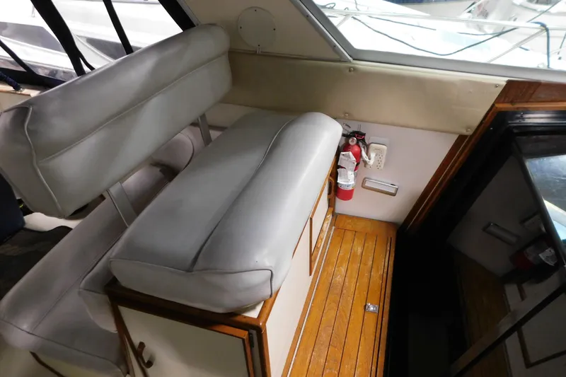 Slide: The Image of 1986 Sea Ray 390 Express Cruiser interior with white seating and wooden flooring. - 16