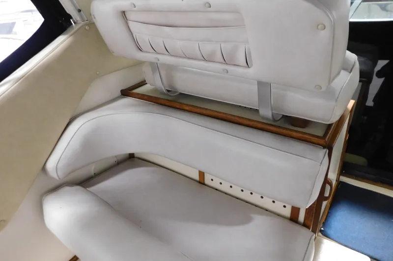 Slide: The Image of 1986 Sea Ray 390 Express Cruiser interior seating with white upholstery and wooden accents. - 20