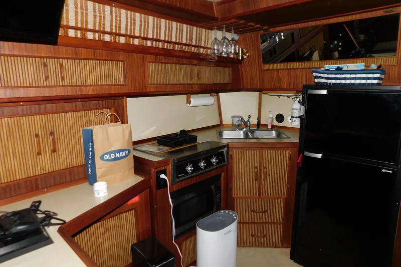 Slide: The Image of 1986 Sea Ray 390 Express Cruiser kitchen with wooden cabinets, stove, and refrigerator. - 21