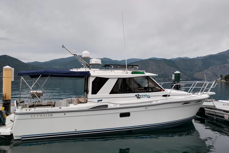 The Image of 2016 Cutwater C-28 LE boat docked on a serene lake with mountainous backdrop. - 0