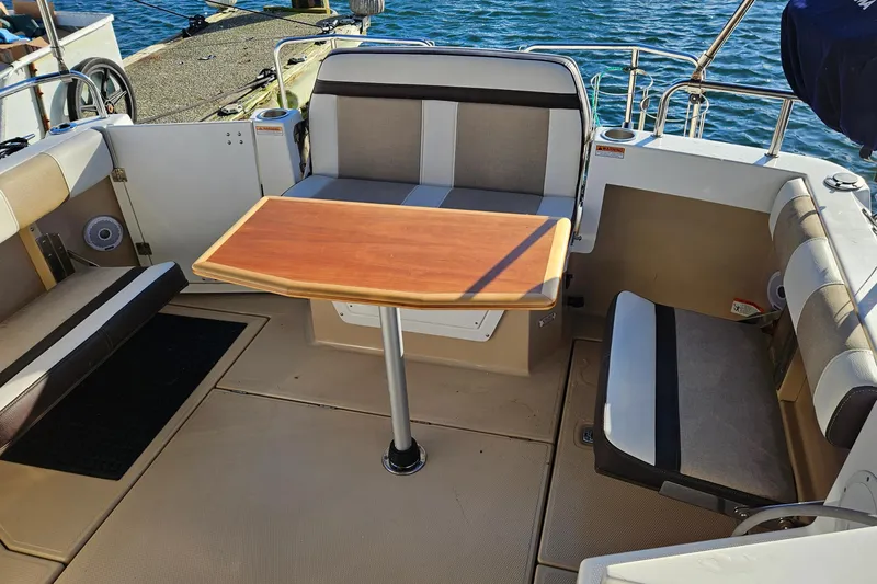 Slide: The Image of 2016 Cutwater C-28 LE boat interior with seating and wooden table, docked by the water. - 26