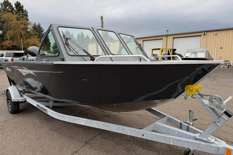 Slide: The Image of 2026 Fish Rite Sportsman 20 boat on trailer, parked outdoors near industrial building. - 7