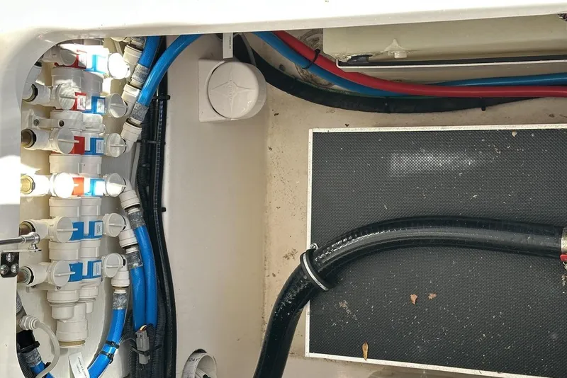 Slide: The Image of 2016 Pursuit DC 325 Dual Console boat plumbing system with blue and red hoses. - 16