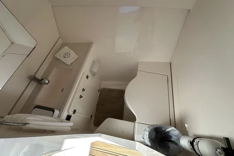 Slide: The Image of Interior of 2016 Pursuit DC 325 Dual Console boat, featuring a compact bathroom area. - 19