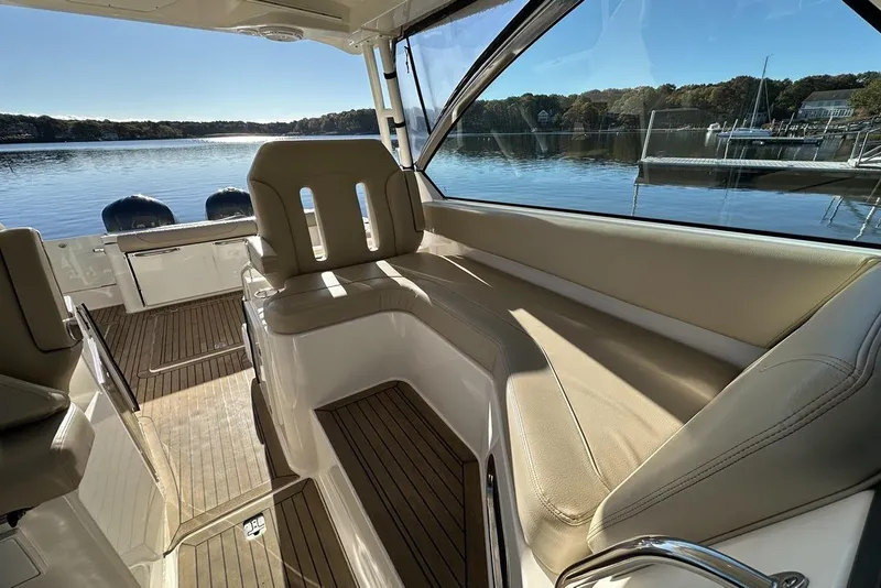 Slide: The Image of 2016 Pursuit DC 325 Dual Console interior with beige seating and scenic lake view. - 35