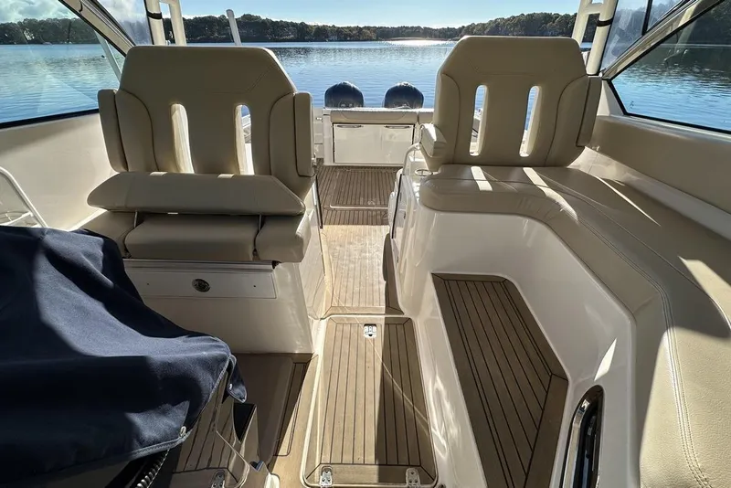 Slide: The Image of 2016 Pursuit DC 325 Dual Console interior with seating, overlooking a serene lake view. - 36