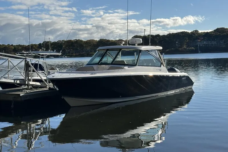 Slide: The Image of 2016 Pursuit DC 325 Dual Console boat docked on calm water under a blue sky. - 38