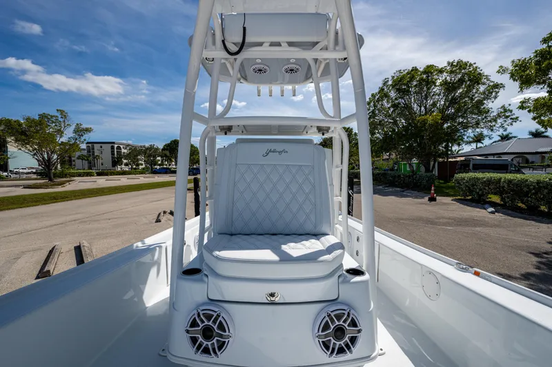 Slide: The Image of 2026 Yellowfin 24 Bay CE boat interior with white seating and speakers, parked outdoors. - 4