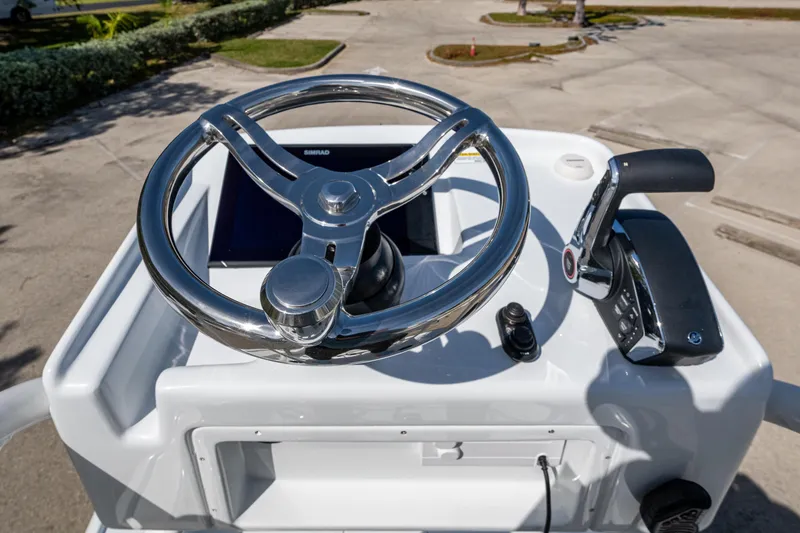 Slide: The Image of Steering console of 2026 Yellowfin 24 Bay CE boat with chrome wheel and controls. - 7