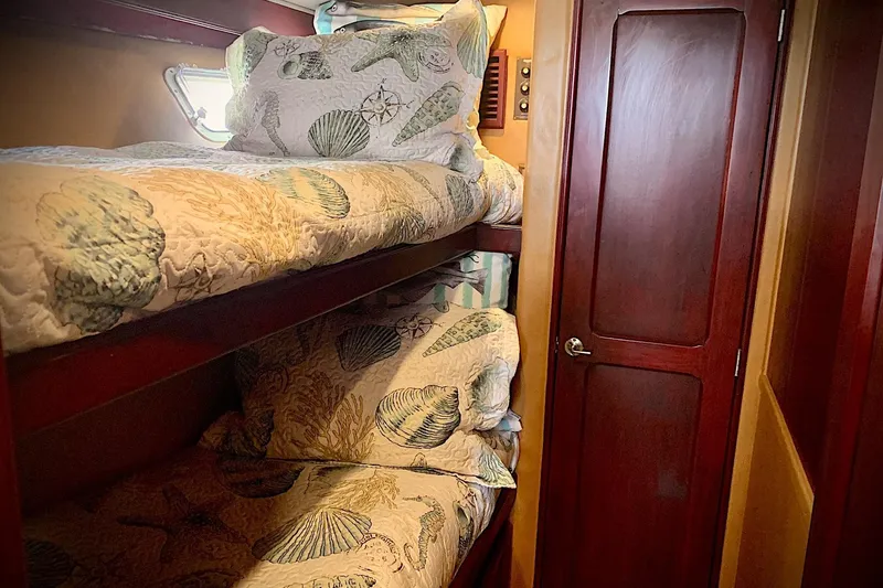 Slide: The Image of Cozy bunk beds in 1984 Egg Harbor 48' Flybridge cabin with nautical-themed bedding. - 13