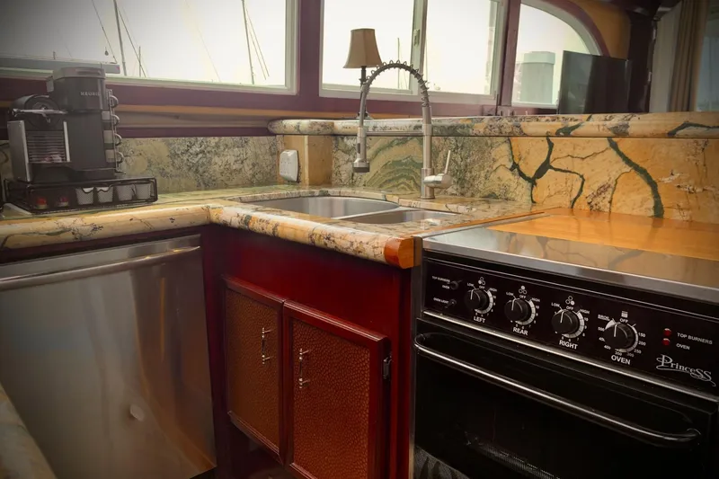 Slide: The Image of 1984 Egg Harbor 48' Flybridge kitchen with marble countertops, stainless steel appliances, and a coffee maker. - 15