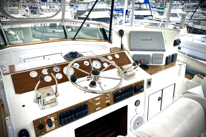 Slide: The Image of 1984 Egg Harbor 48' Flybridge helm with Garmin navigation, gauges, and controls in marina setting. - 19