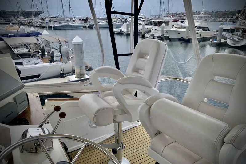 Slide: The Image of 1984 Egg Harbor 48' Flybridge interior with white captain chairs, overlooking marina. - 20