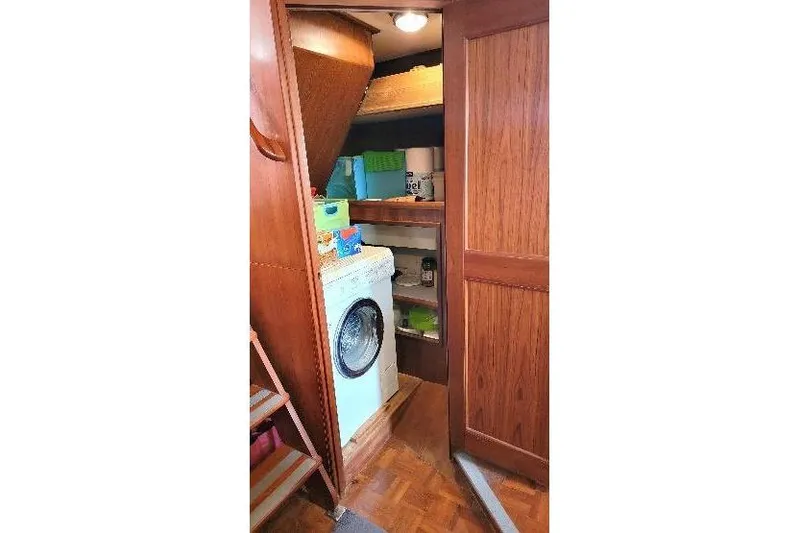 Slide: The Image of Laundry area inside 1998 DeFever 44 Sundeck Trawler with washing machine and storage shelves. - 15