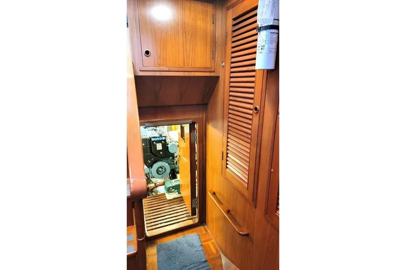 Slide: The Image of 1998 DeFever 44 Sundeck Trawler interior with wooden cabinetry and engine room access. - 18