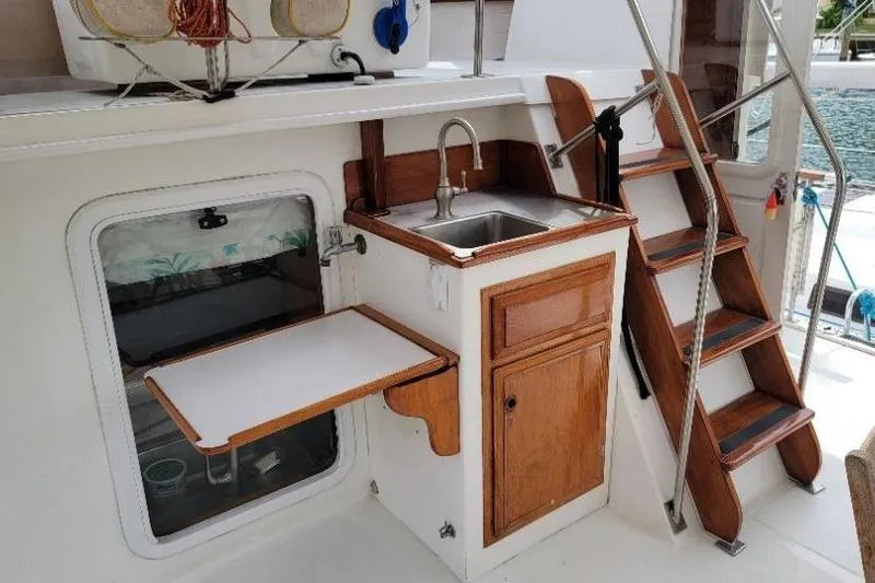 Slide: The Image of 1998 DeFever 44 Sundeck Trawler interior with sink, wooden cabinetry, and stairs. - 19