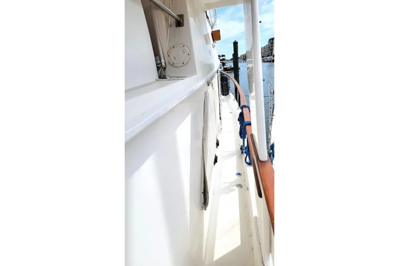 Slide: The Image of Side deck view of 1998 DeFever 44 Sundeck Trawler, featuring wooden railings and marina backdrop. - 22