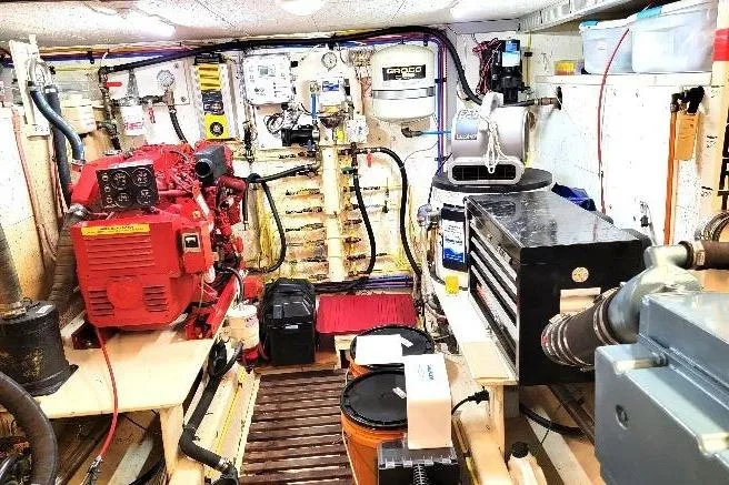 Slide: The Image of Engine room of 1998 DeFever 44 Sundeck Trawler with red engine and organized tools. - 28