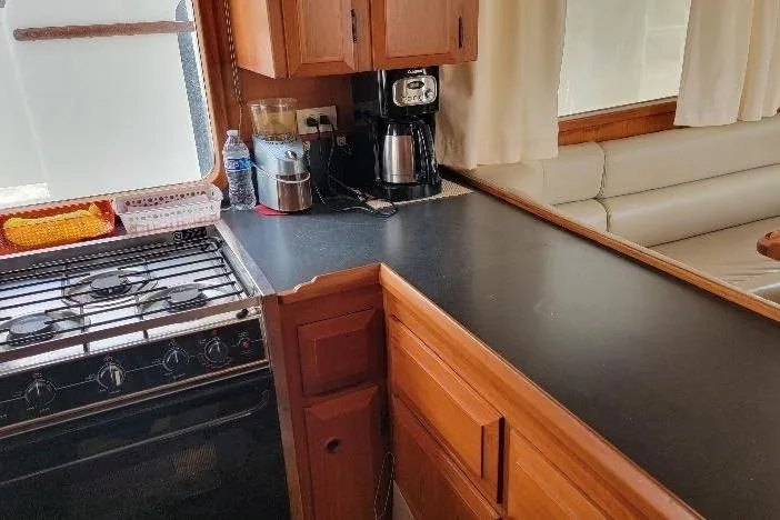 Slide: The Image of 1998 DeFever 44 Sundeck Trawler kitchen with stove, counter, and seating area. - 7