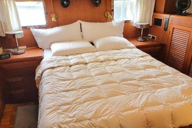Slide: The Image of Cozy bedroom in 1998 DeFever 44 Sundeck Trawler with plush bedding and wooden accents. - 9