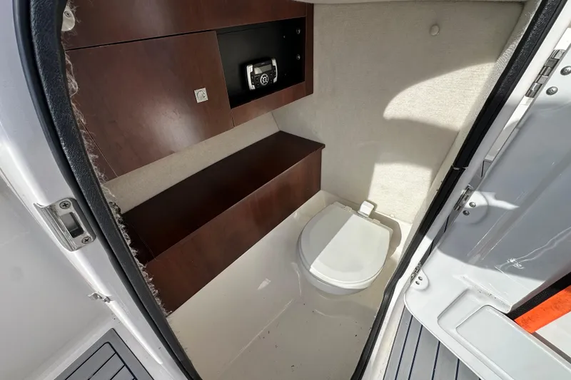 Slide: The Image of 2016 Robalo R227 Dual Console boat interior with compact marine toilet and storage. - 10
