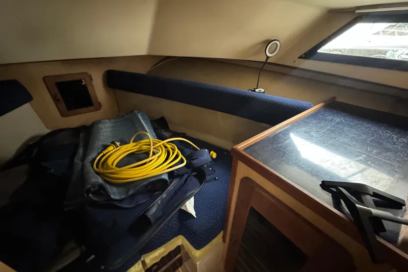 Slide: The Image of 1986 Stamas Flybridge Sedan cabin interior with storage, window, and coiled yellow cable. - 10
