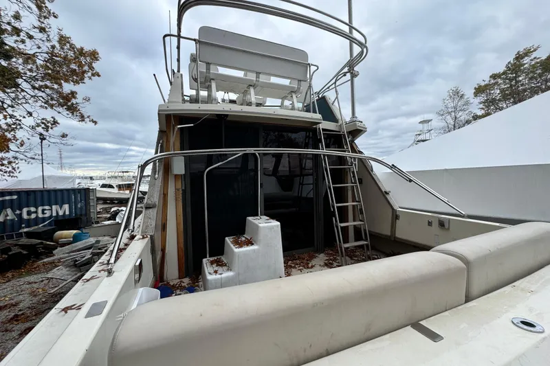 Slide: The Image of 1986 Stamas Flybridge Sedan boat with ladder and seating, docked outdoors. - 2