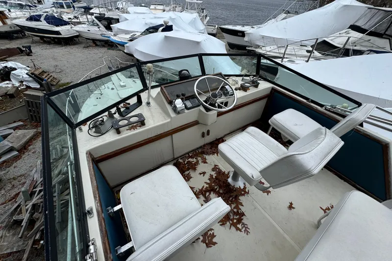 Slide: The Image of 1986 Stamas Flybridge Sedan boat interior with steering wheel, seats, and fallen leaves. - 3