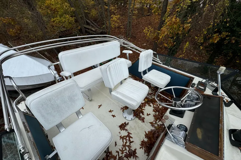 Slide: The Image of 1986 Stamas Flybridge Sedan with white seating, steering wheel, and autumn leaves on deck. - 4