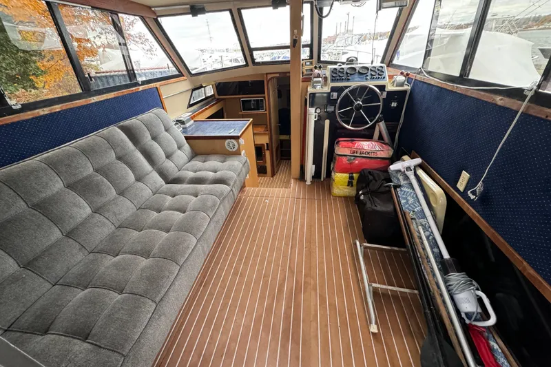 Slide: The Image of 1986 Stamas Flybridge Sedan interior with gray seating, wooden flooring, and navigation controls. - 6