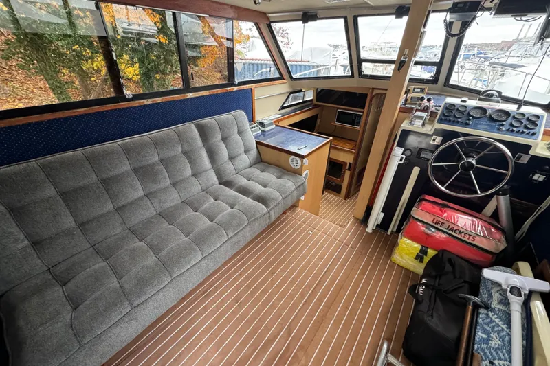 Slide: The Image of 1986 Stamas Flybridge Sedan interior with gray sofa, steering wheel, and life jackets. - 7