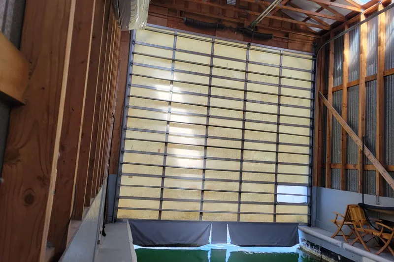 Slide: The Image of Interior of a 2005 BoatHouse with large door and wooden seating. - 4