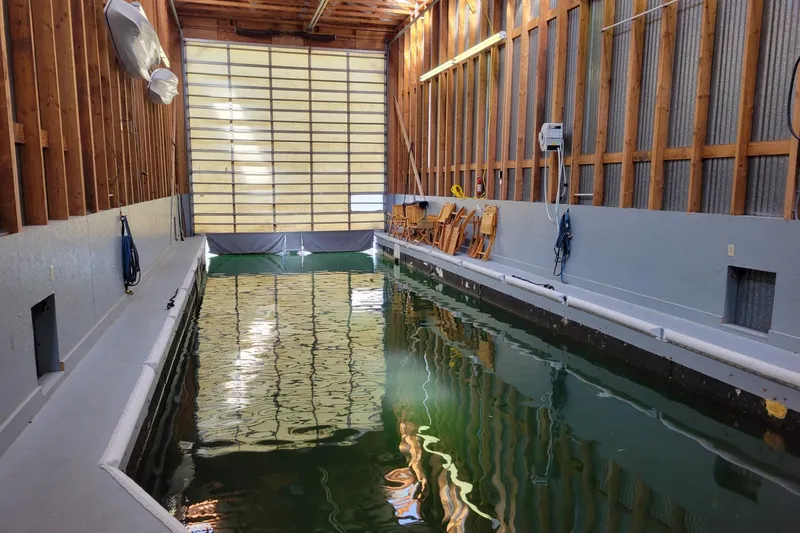 Slide: The Image of Indoor boathouse with water channel, wooden walls, and stacked chairs, BoatHouse model, 2005. - 5