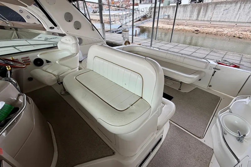 Slide: The Image of 1999 Sea Ray 400 Sundancer interior with white seating and helm, docked by the water. - 14